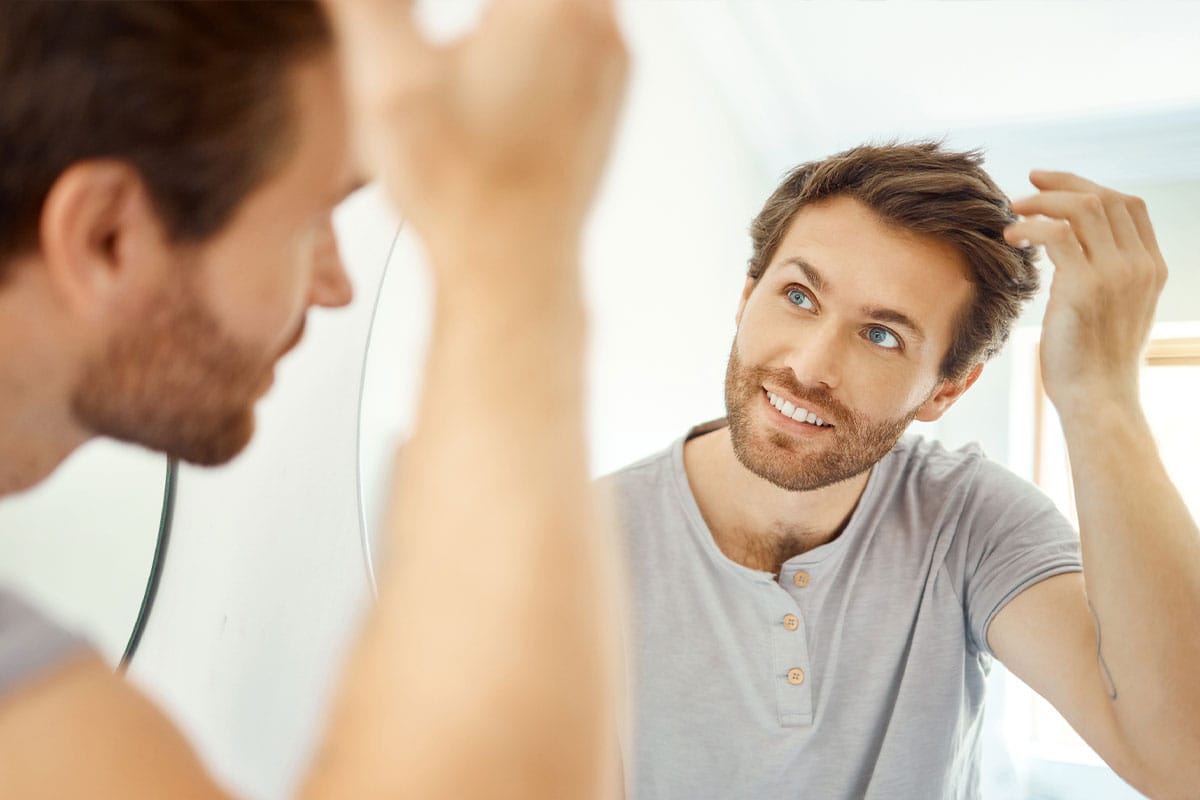 man looking in the mirror after his hair transplant in Gulf Shores, AL