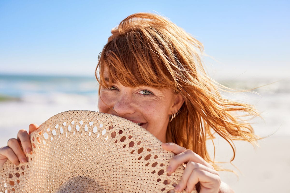 young woman smiling on the beach after getting facial rejuvenation treatments in Gulf Shores, AL