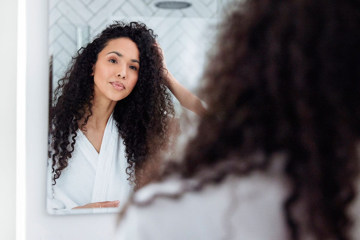 woman looking in the mirror after getting hair restoration treatment in Gulf Shores, FL